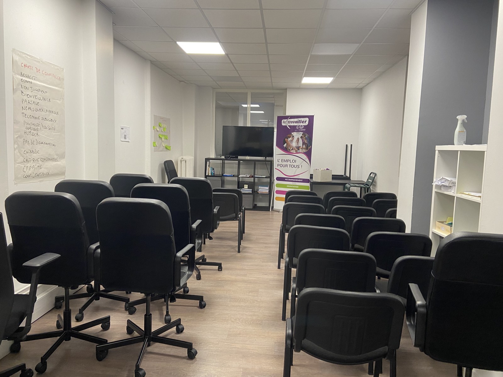 Salle d'accueil et d'information d'un site Retravailler EGP, avec kakémono « L'emploi pour tous » et charte de confiance affichée